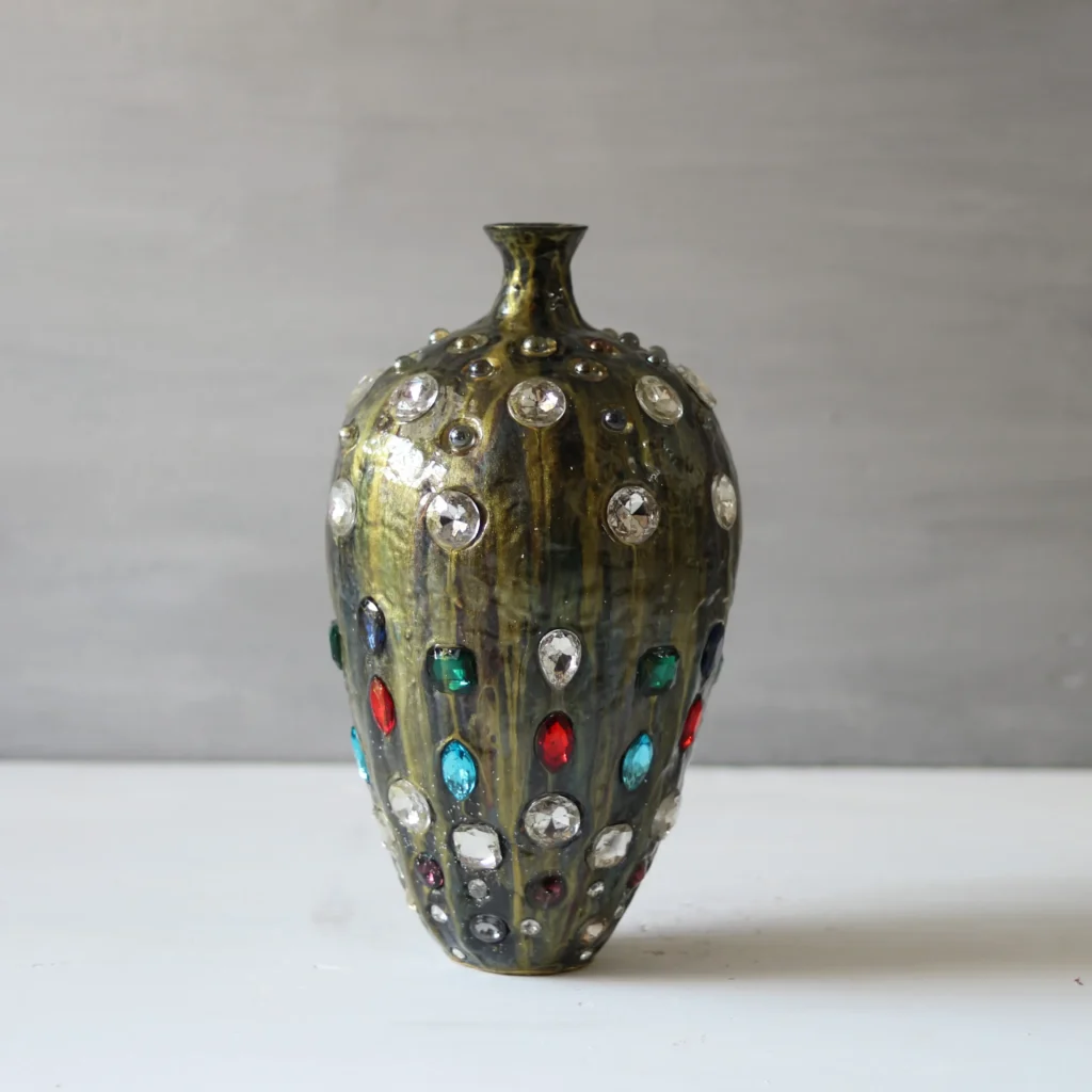 Golden black sculptural vase with embedded glass crystals, glow-in-the-dark mineral clay art.