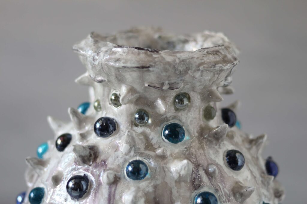Macro detail of hand-sculpted mineral clay and embedded glass.